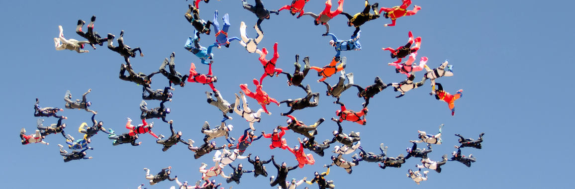 Das Bild zeigt eine Formation von Fallschirmspringer_innen.